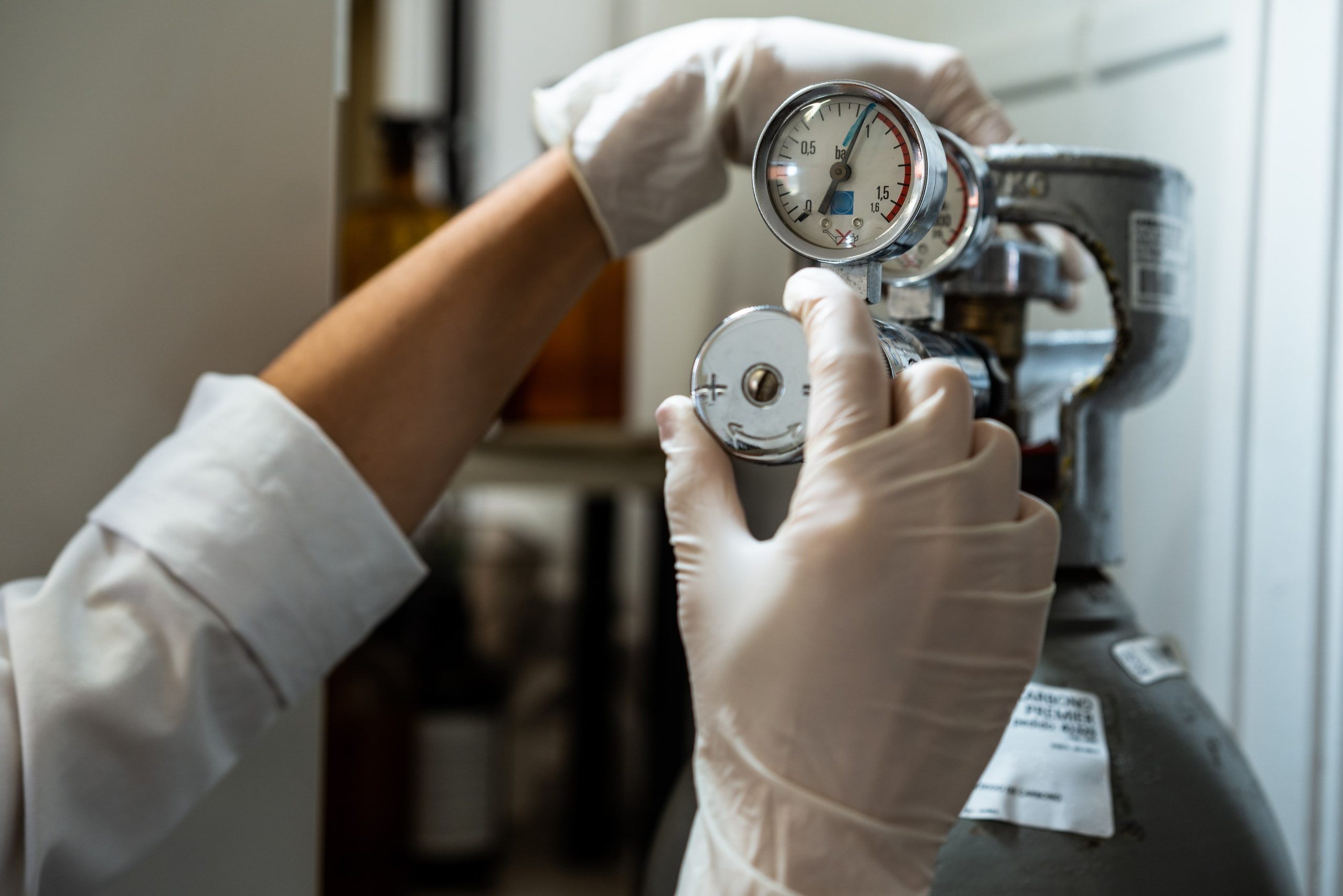 a person wearing white gloves is holding a gauge with the number 12 on it