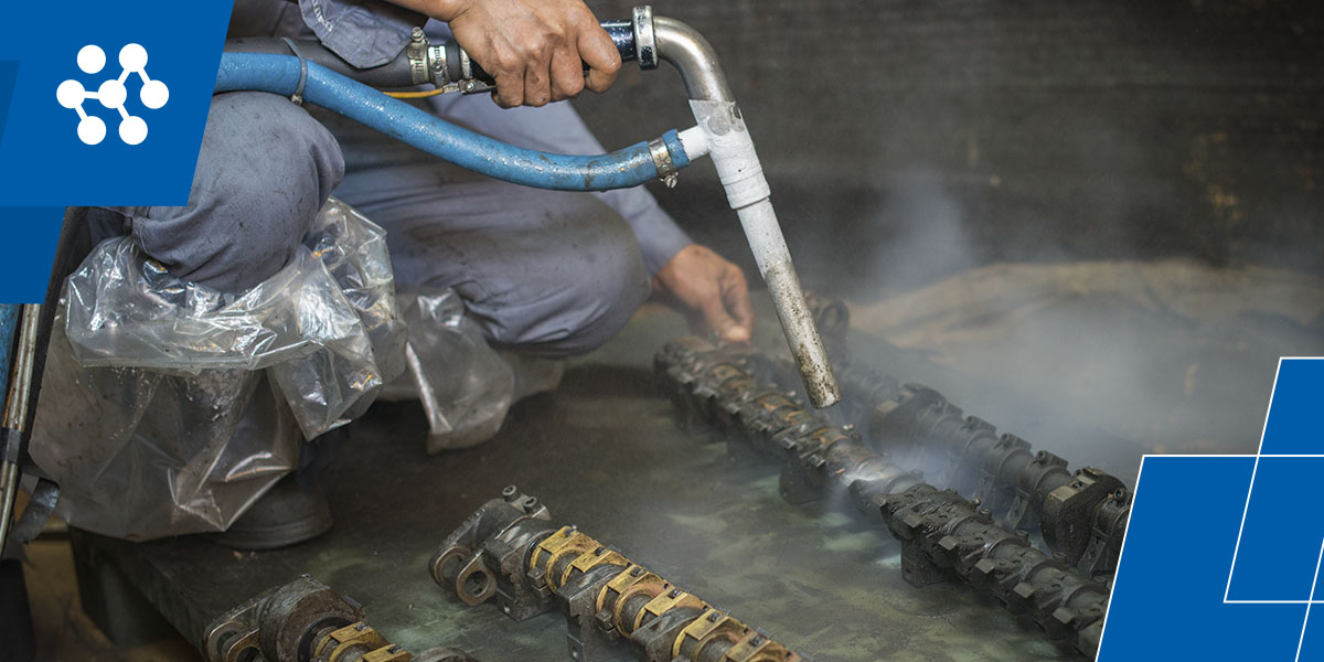 a man is using a hose to clean a piece of metal