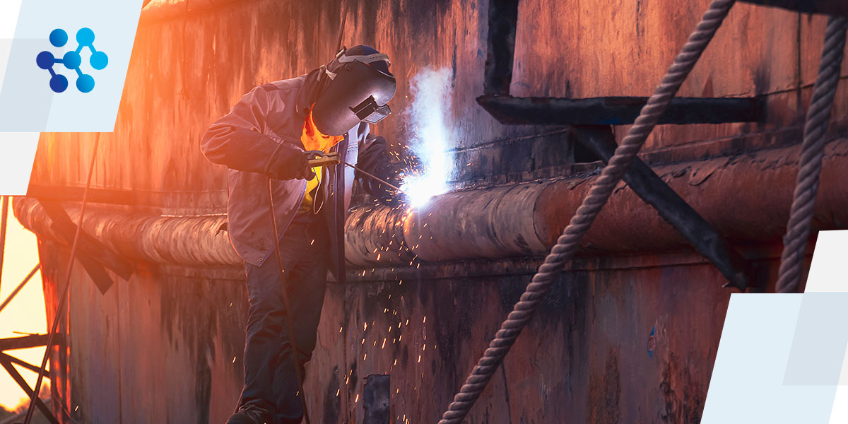 a man wearing a welding mask is welding a pipe