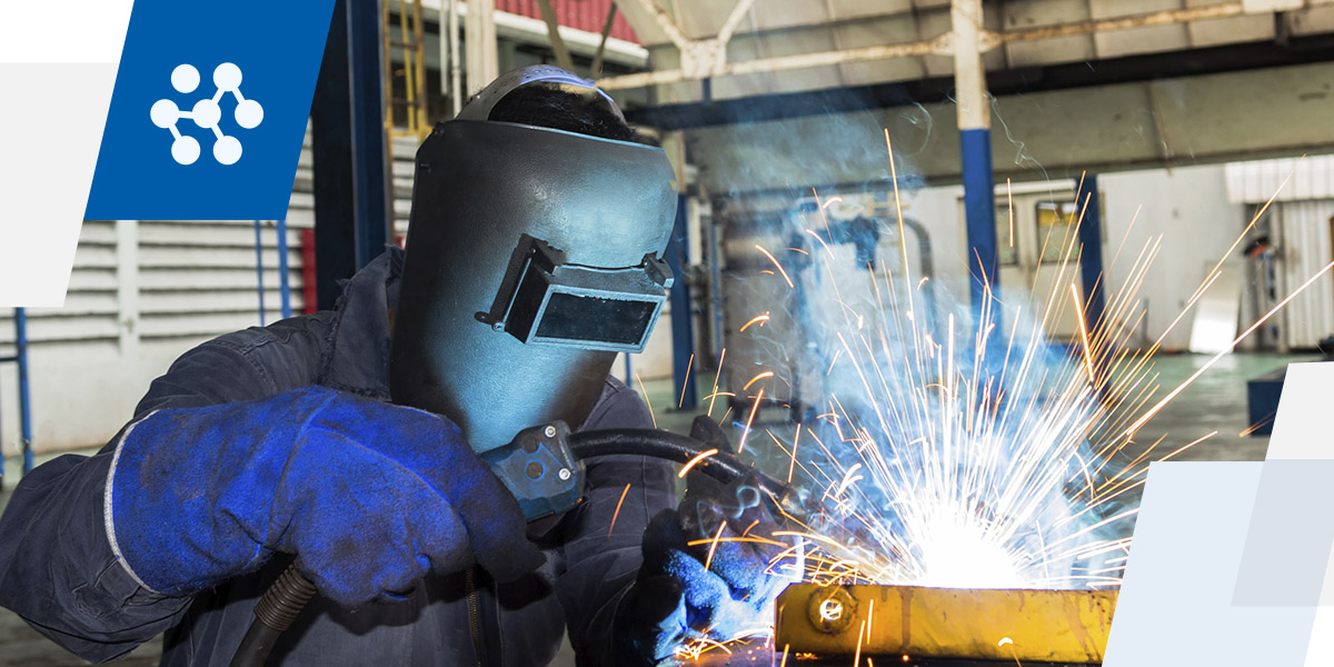 a man wearing a welding mask is welding a piece of metal